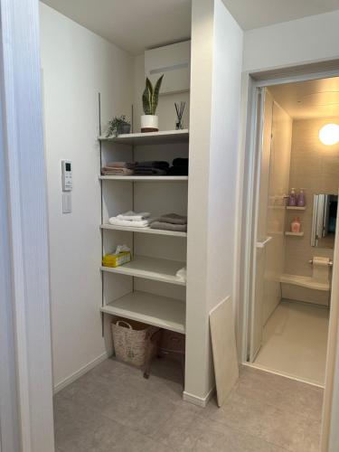 a walk in closet with white shelves in a bathroom at yuanquanHOTEL in Osaka