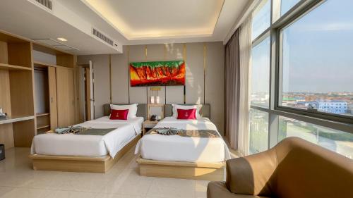 two beds in a room with a large window at Elegant Airport Hotel in Bangkok