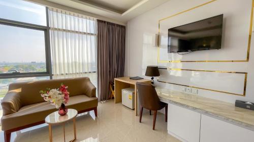 a hotel room with a couch and a desk and a tv at Elegant Airport Hotel in Bangkok