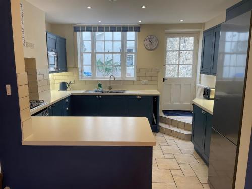 a large kitchen with blue cabinets and a sink at Safe Harbour in Weymouth