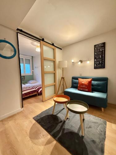 a living room with a blue couch and two tables at Central Océan in Les Sables-d'Olonne