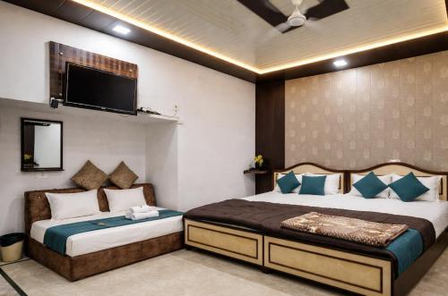 a bedroom with two beds and a tv on the wall at Hotel Swarajya Palace in Agra