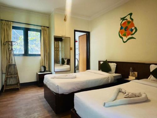 a hotel room with two beds and a mirror at Boudha Orange Hotel in Kathmandu