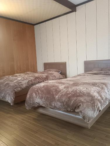 two beds sitting in a room with wood floors at 波松の家 in Awara