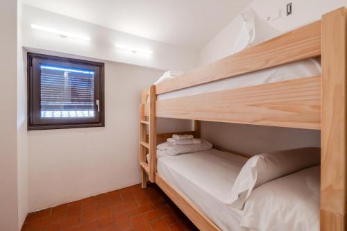 two bunk beds in a small room with a window at Flateli Santa Clara 31 in Girona