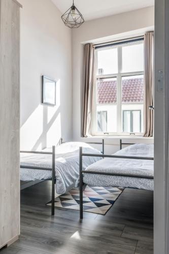 two beds in a bedroom with a window at The Carriage House - Historic 3-Bedroom Apartment near Utrecht - Huize de Lekpoort Vianen in Vianen