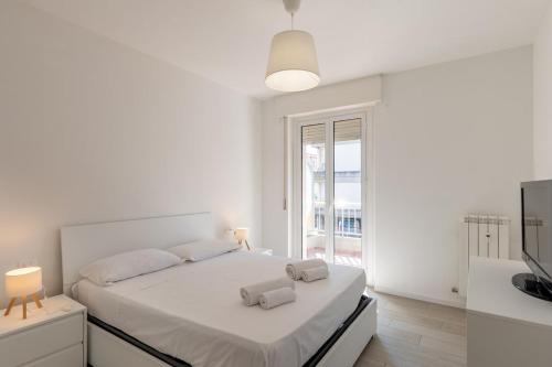 a white bedroom with a large bed and a window at Les Fleurs Pool Residence in Bordighera
