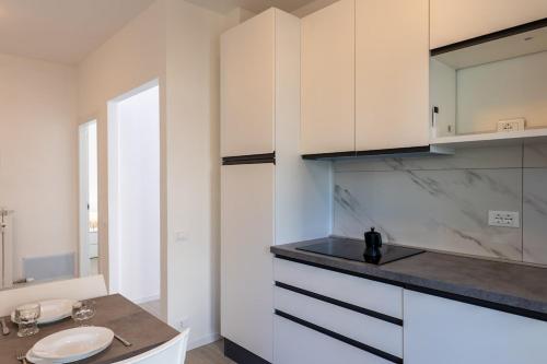 a kitchen with white cabinets and a sink at Les Fleurs Pool Residence in Bordighera