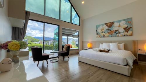 a bedroom with a bed and a large window at Gaia Pool Villa Khao Yai in Ban Bung Toei