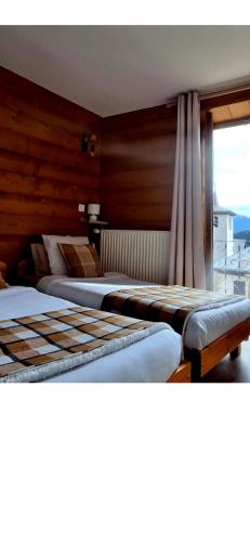 a bedroom with two beds and a window with a view at Auberge de l'eau rousse in La Léchère
