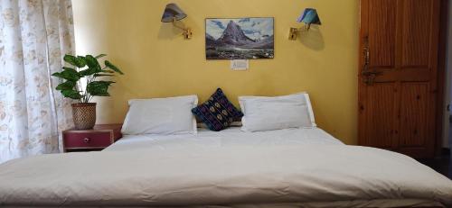 a bed with white sheets and pillows in a bedroom at Hotel T-Suru Leh in Leh
