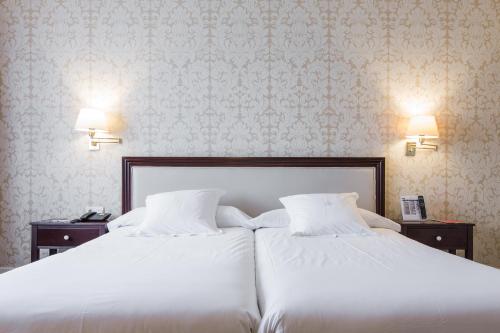 two white beds in a bedroom with wallpaper at Hotel Carlton in Bilbao