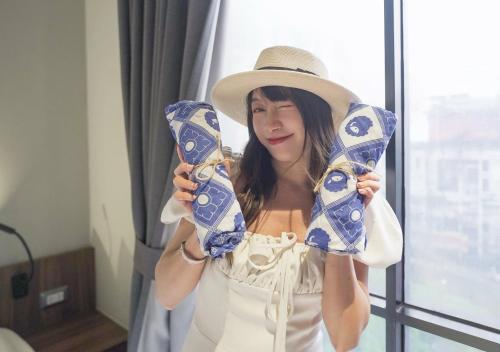 a woman wearing a hat holding a pair of shoes at Kokotel Bangkok Surawong in Bangkok