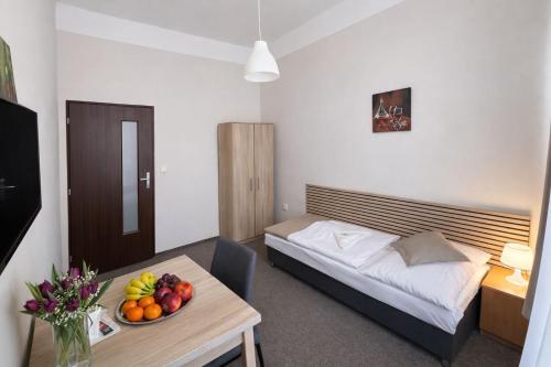 a bedroom with a bed and a table with a bowl of fruit at Hotel Hůrka in Pardubice
