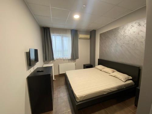 a small bedroom with a bed and a television at Lifto Hostel in Voyvodinovo