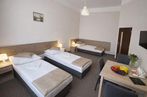 a hotel room with two beds and a table at Hotel Hůrka in Pardubice