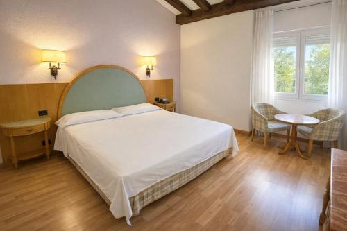 a bedroom with a large white bed and a table at Gran Hotel Los Angeles in Getafe