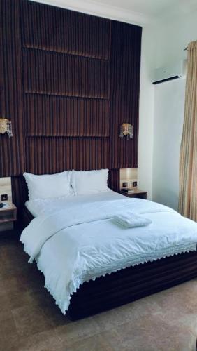 a bedroom with a large white bed with a wooden headboard at Meglams Hotel and Suite in Yenagoa