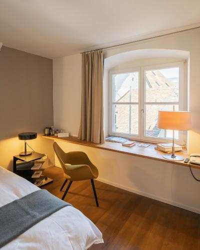 a bedroom with a window and a chair and a desk at Baseltor Hotel & Restaurant in Solothurn