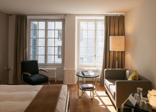 a hotel room with a bed and a chair and a table at Baseltor Hotel & Restaurant in Solothurn