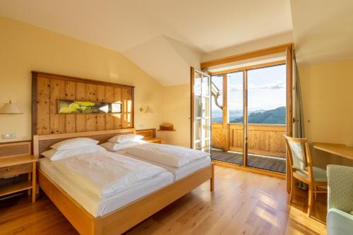 a bedroom with a bed and a desk and a window at das kappel wein gut hotel in Kitzeck im Sausal