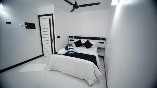 a white bedroom with a bed and a ceiling fan at Alyraa Sunset Mathiveri - Free Picnic Island Trip Included in Mathiveri
