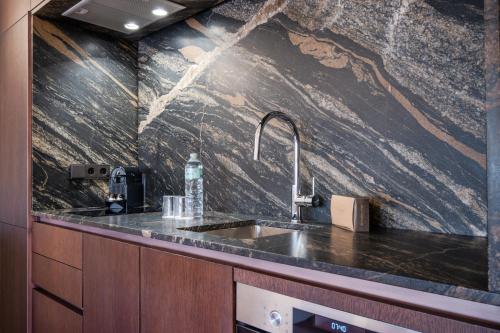 a kitchen with a sink and a marble wall at Flateli Santa Clara 22 in Girona