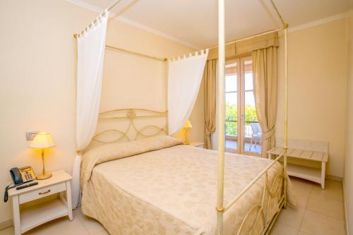 a bedroom with a canopy bed and a balcony at Incantea Resort in Tortoreto Lido