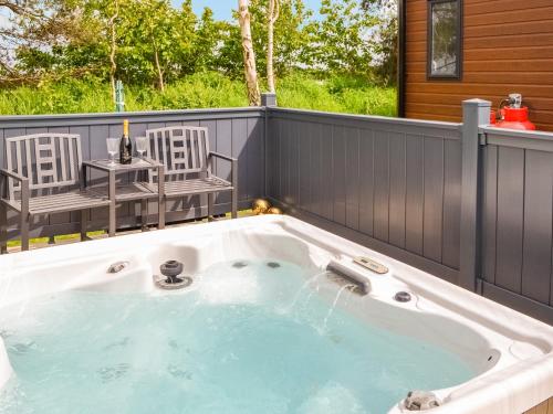 a jacuzzi tub on a patio with two chairs at Baywood View in East Heslerton
