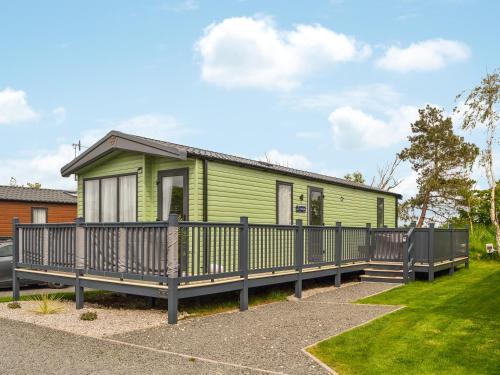 a green house with a wooden porch at Baywood View in East Heslerton