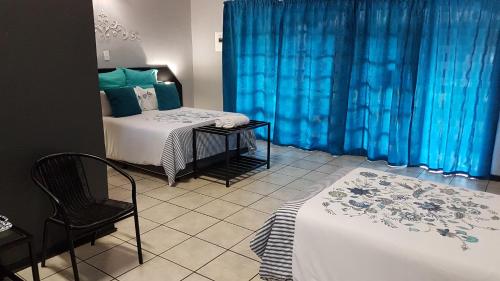 a bedroom with a bed and a chair and blue curtains at Siesta Guest House in Musina