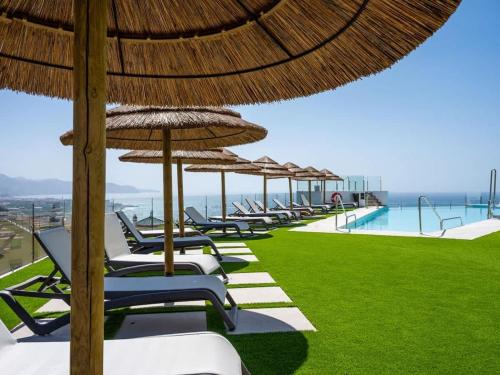 a row of lounge chairs with umbrellas and a pool at Luxury 2 Bedrooms Apartment Bayview Hills Nerja in Torrox
