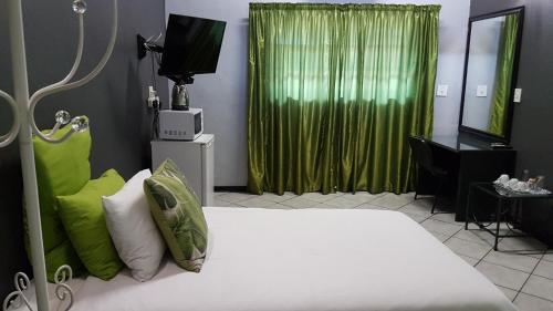 a bedroom with a white bed and a green curtain at Siesta Guest House in Musina
