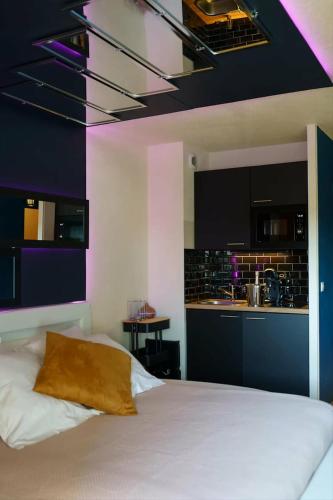 a bedroom with a white bed and a kitchen at love room, sauna et balnéo in Perros-Guirec