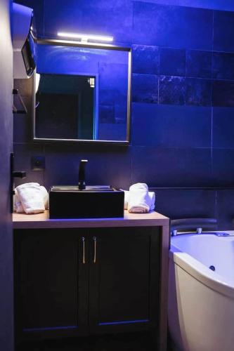 a bathroom with a sink and a tub and a mirror at love room, sauna et balnéo in Perros-Guirec