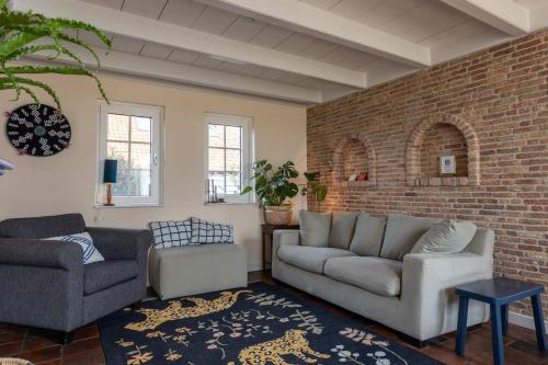 a living room with two couches and a brick wall at Het Grote Huis at Buitenplaats Zeeuwse Liefde in Westkapelle