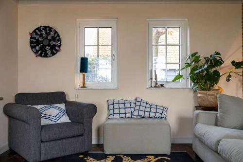 a living room with a couch and a chair and windows at Het Grote Huis at Buitenplaats Zeeuwse Liefde in Westkapelle