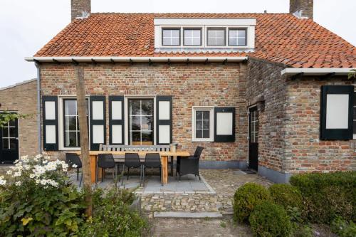 a brick house with a wooden table and chairs at Het Grote Huis at Buitenplaats Zeeuwse Liefde in Westkapelle