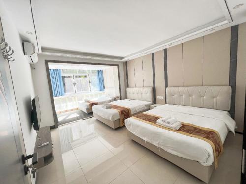 a hotel room with two beds and a window at Yalong Sea Joy in Sanya