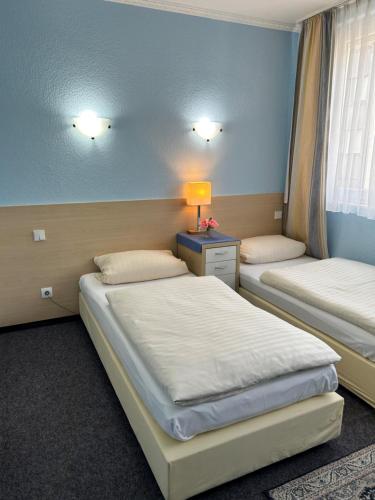 a bedroom with two beds and a lamp on a table at Hotel Jägerhof in Wiesbaden