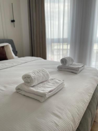 two towels on a white bed with a window at Cashmere Apartment in Cluj-Napoca