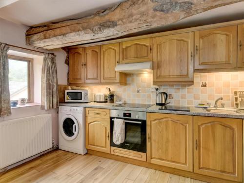 a kitchen with wooden cabinets and a washer and dryer at Cleeve- Ukc4922 in Timberscombe