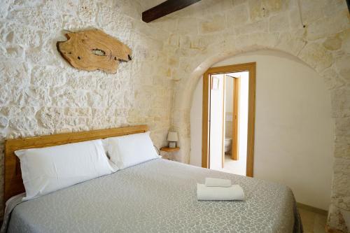 a bedroom with a bed in a stone wall at Trulli Loco in Locorotondo