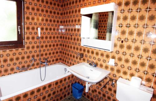 W łazience znajduje się umywalka i wanna. w obiekcie Kontiki w mieście Saas-Fee