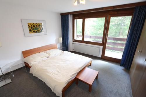 a bedroom with a bed and a large window at Kontiki in Saas-Fee