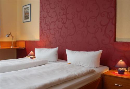 a bedroom with two beds and a red wall at Hotel Hohenzollern in Schleswig