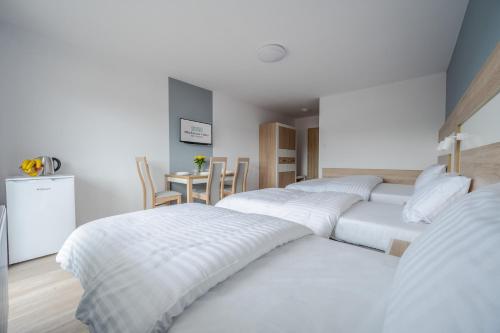 a room with three beds and a table with chairs at Błękitna Fala Resort in Dąbki
