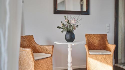 a table with a vase of flowers sitting between two chairs at Hotel Hirschen in Freiburg-Lehen in Freiburg im Breisgau