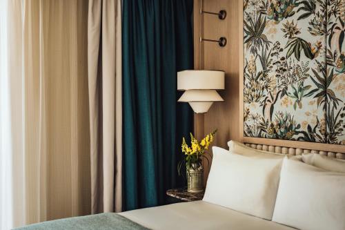 a bedroom with a bed with a lamp and a curtain at The Phoenicia Malta - The Leading Hotels of the World in Valletta