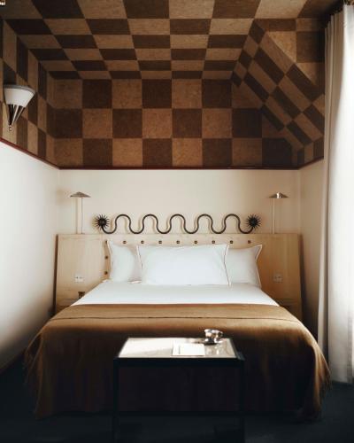 ein Schlafzimmer mit einem großen Bett und einer schachbrettartig gemusterten Decke in der Unterkunft Hôtel Luxia & Spa in Paris